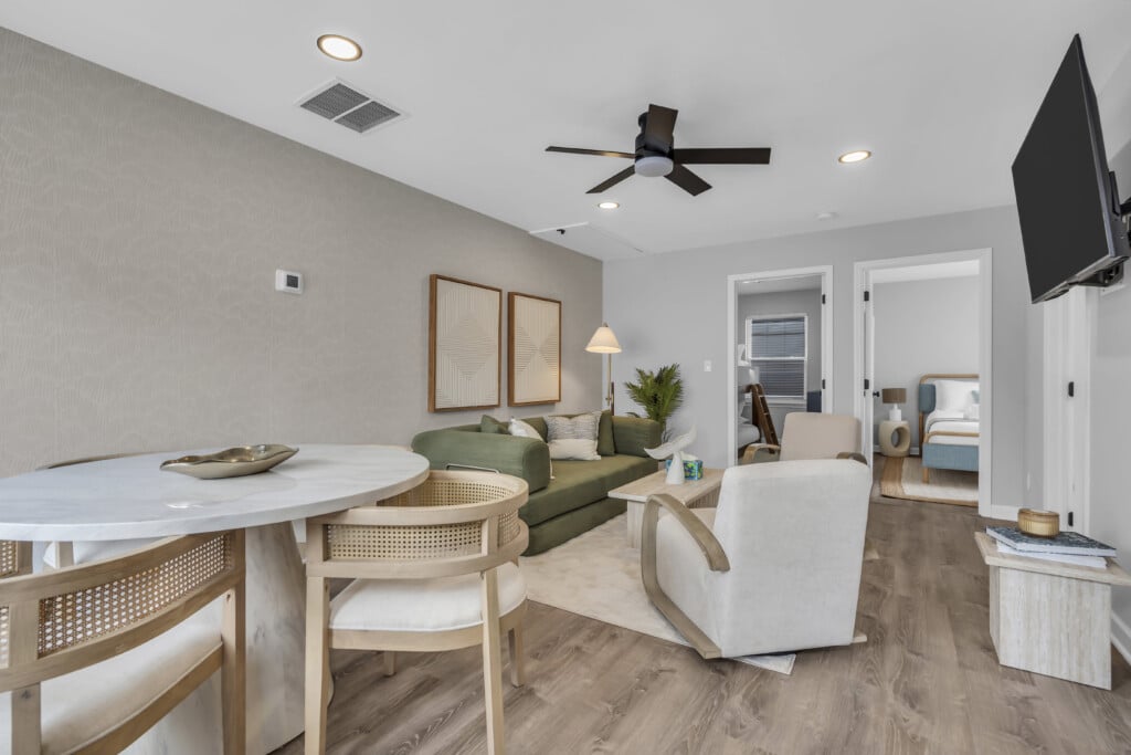 Modern living room in a Jersey Shore vacation rental, featuring a green sofa, round dining table, and decorative accents, showcasing the comfortable and stylish interior ideal for short-term rentals.