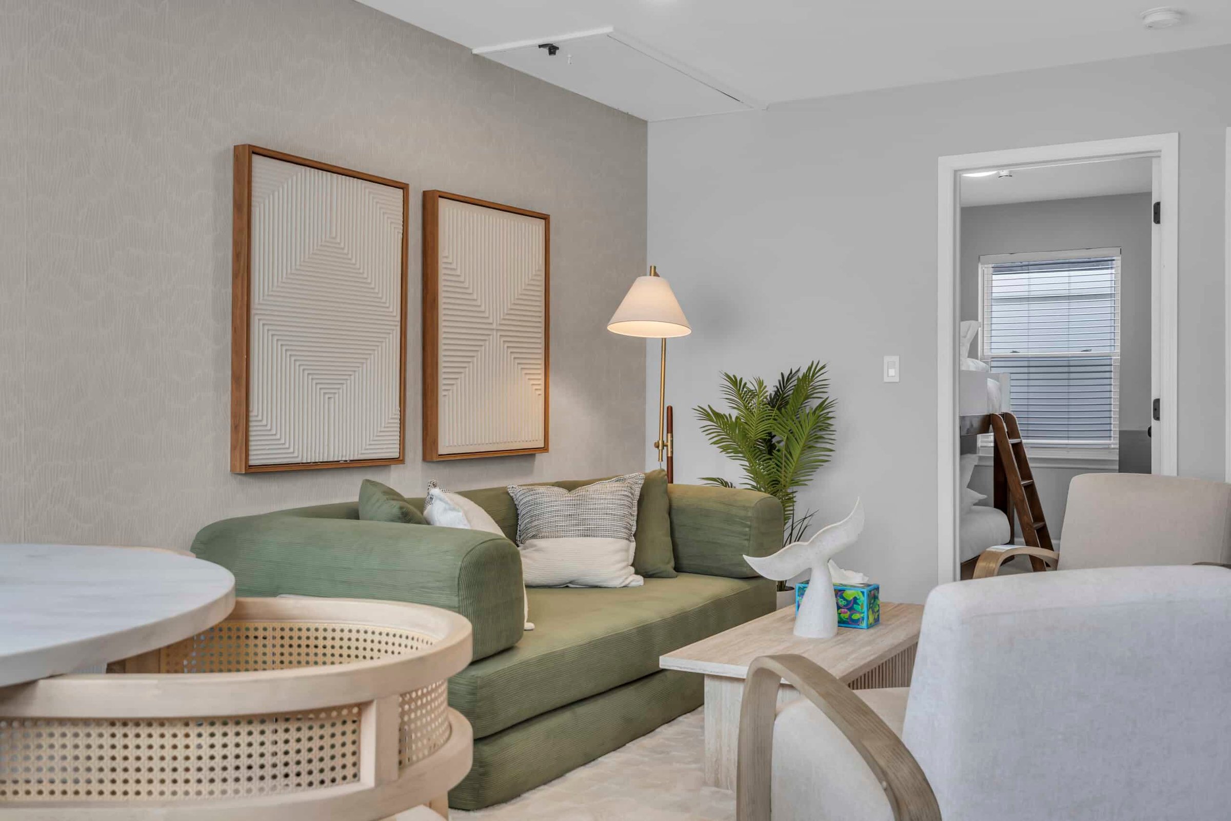 Cozy living room in a Jersey Shore vacation rental with green sofa, decorative wall art, and modern furnishings, promoting beachside relaxation and comfort.