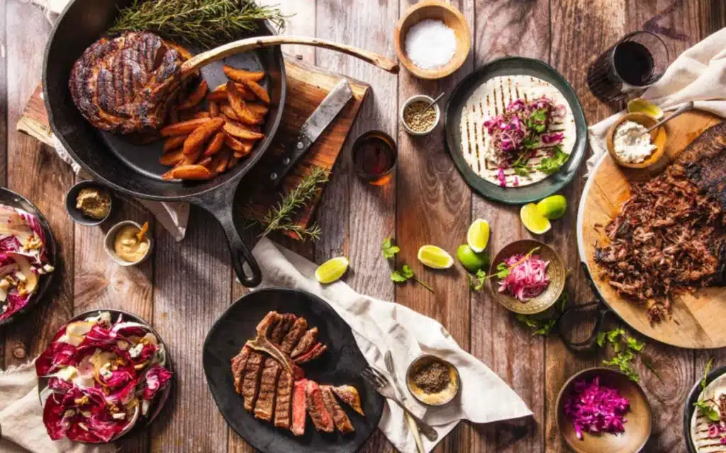 Stylish steak and sides served in a cast iron skillet, featuring New York strip, sweet potato fries, and fresh garnishes, set in a cozy dining atmosphere.