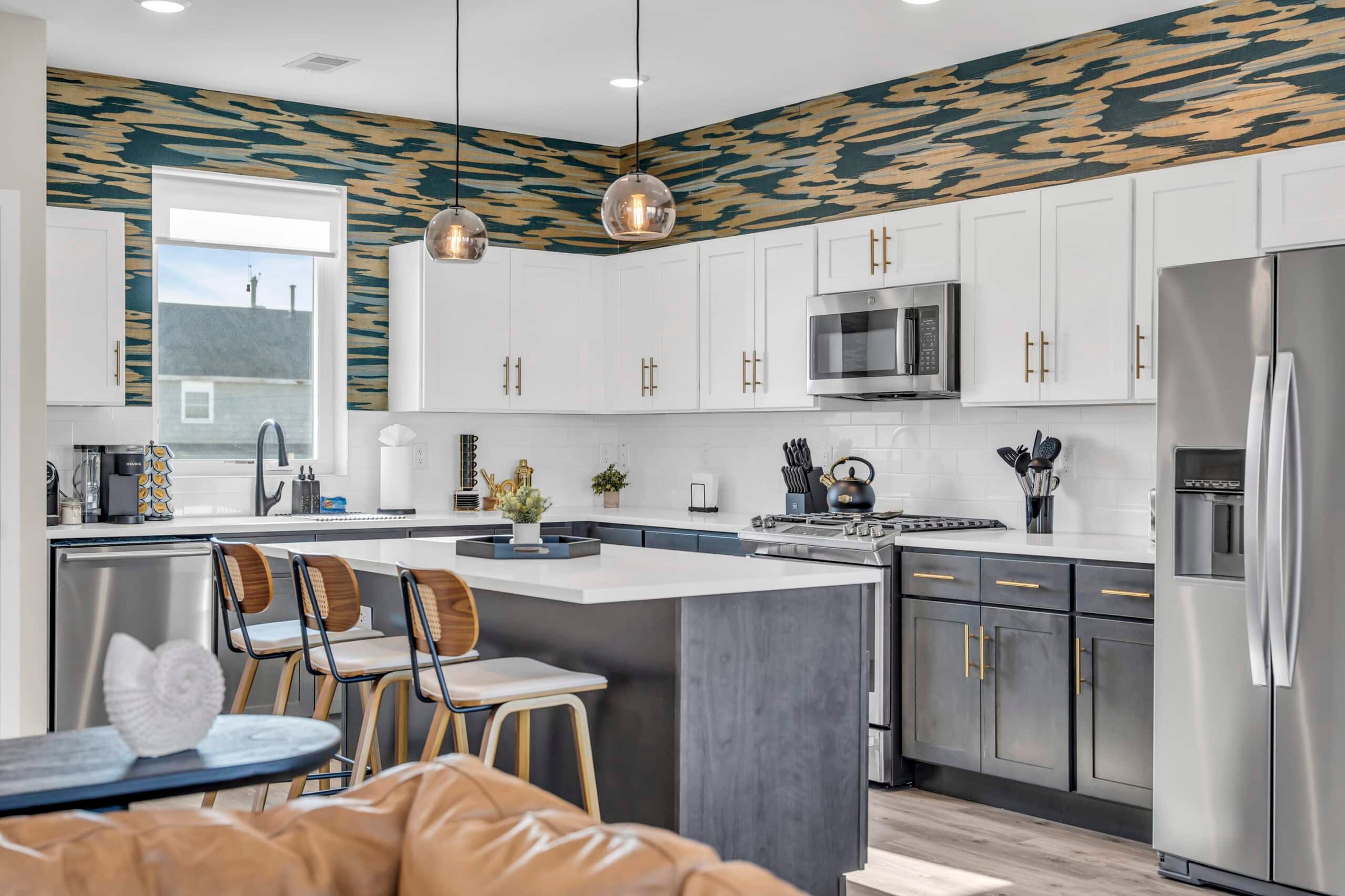 Modern kitchen in a Jersey Shore vacation rental featuring white cabinetry, sleek stainless steel appliances, and stylish decor, ideal for entertaining during beach getaways.
