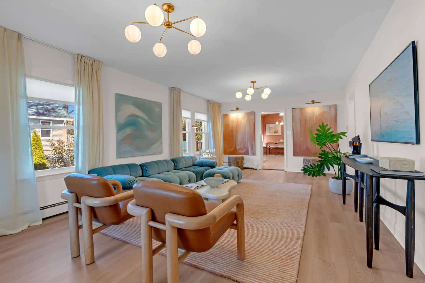Modern living room featuring a blue sectional sofa, stylish light fixtures, and decorative artwork, emphasizing a comfortable and inviting space for short-term rental guests.