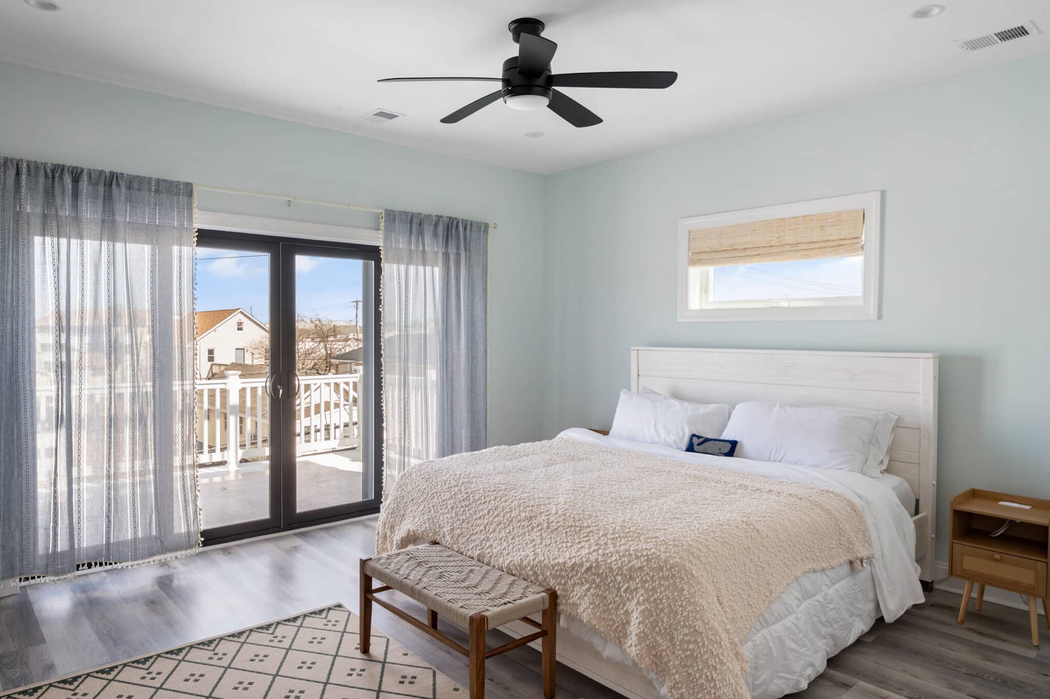 Comfortable Breezy Beach Stays bedroom with made bed, fresh linens, and sliding glass doors to the shore.