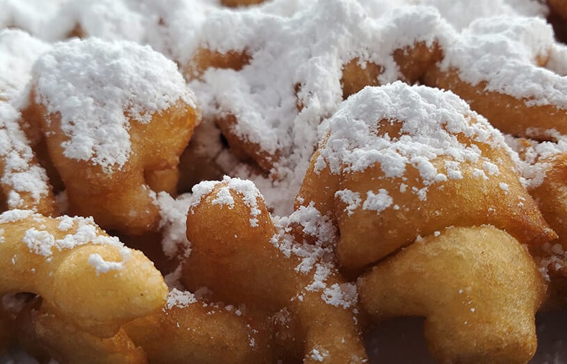 Funnel cake topped with powdered sugar, showcasing its crispy exterior and soft interior, embodying a classic boardwalk treat experience.