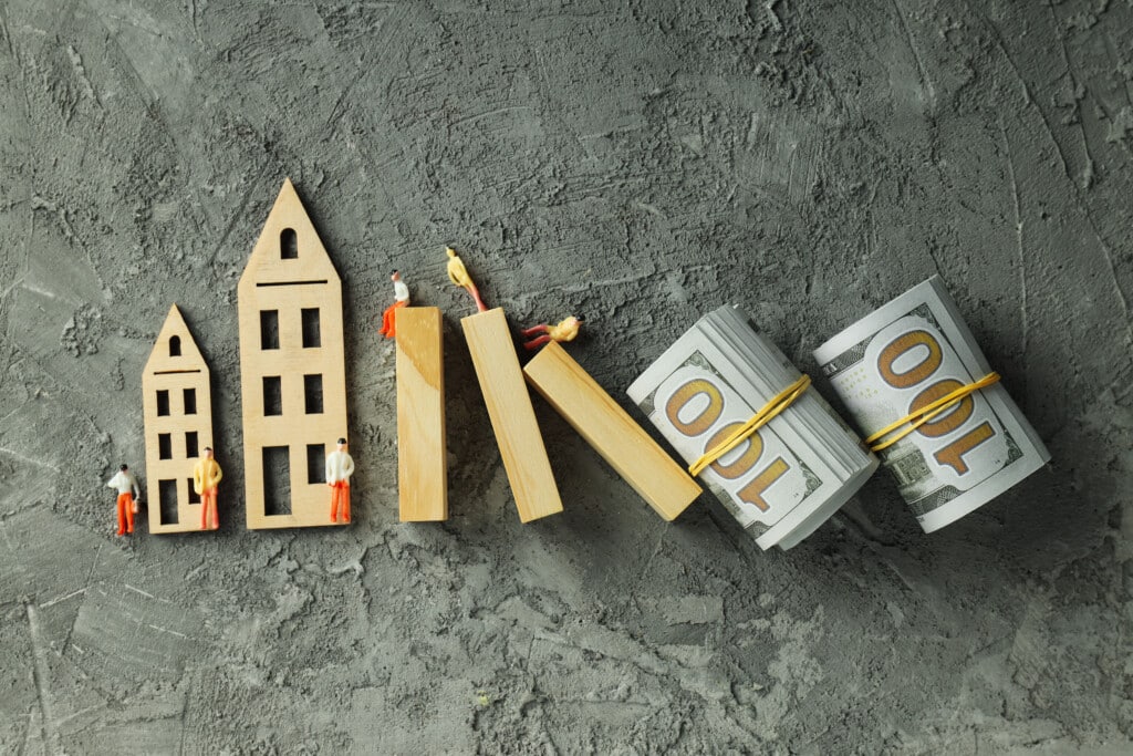 Wooden house models and miniature figures with stacks of cash, symbolizing investment in vacation rental properties and financial growth.