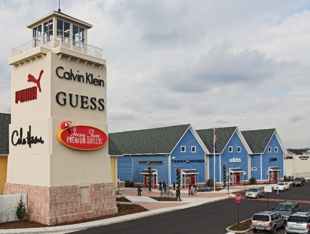 Jersey Shore Premium Outlets featuring designer brand stores like Calvin Klein, Guess, and Adidas, with shoppers exploring the outdoor mall setting.