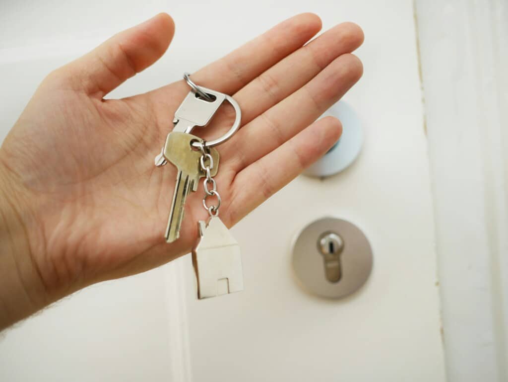 Hand holding house keys with keychain, symbolizing property ownership and investment potential in the Jersey Shore real estate market.