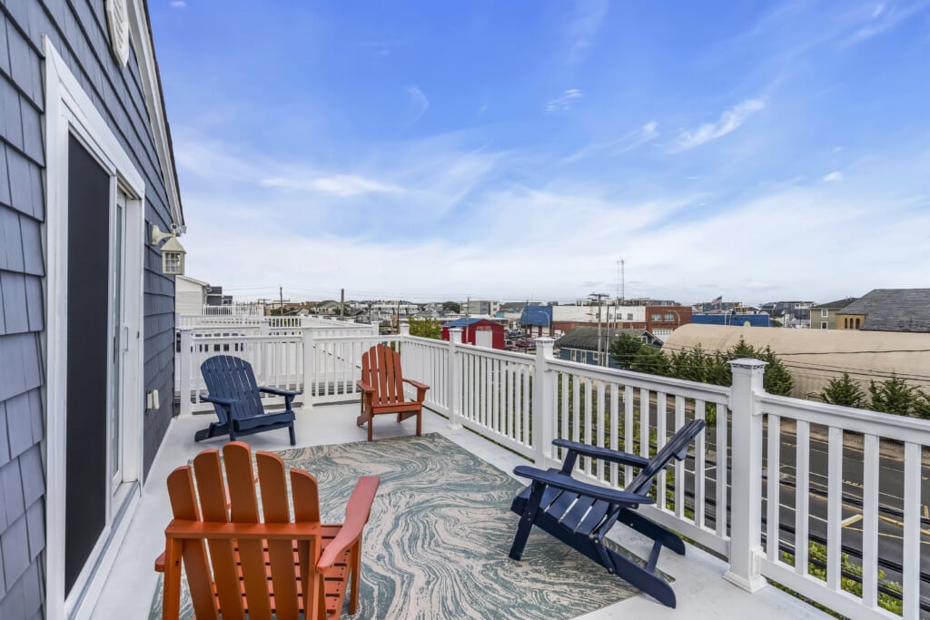 Rooftop deck with colorful Adirondack chairs overlooking Jersey Shore town, highlighting investment potential in vacation rentals and proximity to beach access.