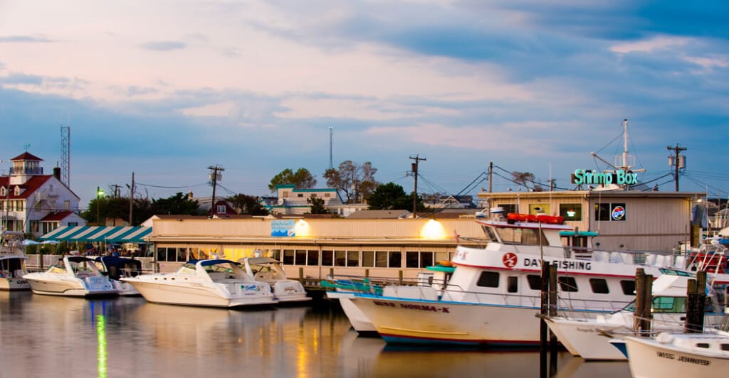 The Shrimp Box restaurant along the Manasquan River, featuring boats docked in front and a scenic waterfront atmosphere, embodying the coastal dining experience at the Jersey Shore.