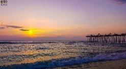 a fishing pier and ocean during sunrise