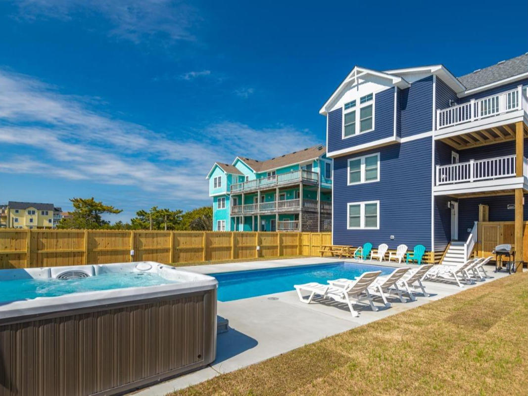 backyard of a blue house with a hottub and pool