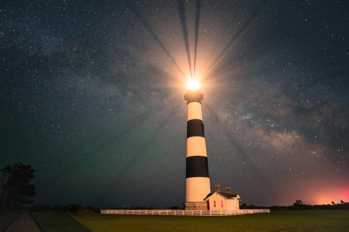 black and white striped lighthouse at night with the milkyway in the sky