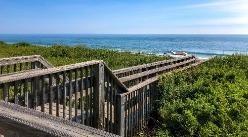 a boardwalk leading you to the beach with the ocean in the background