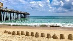 sand castles in front of a pier on the beach