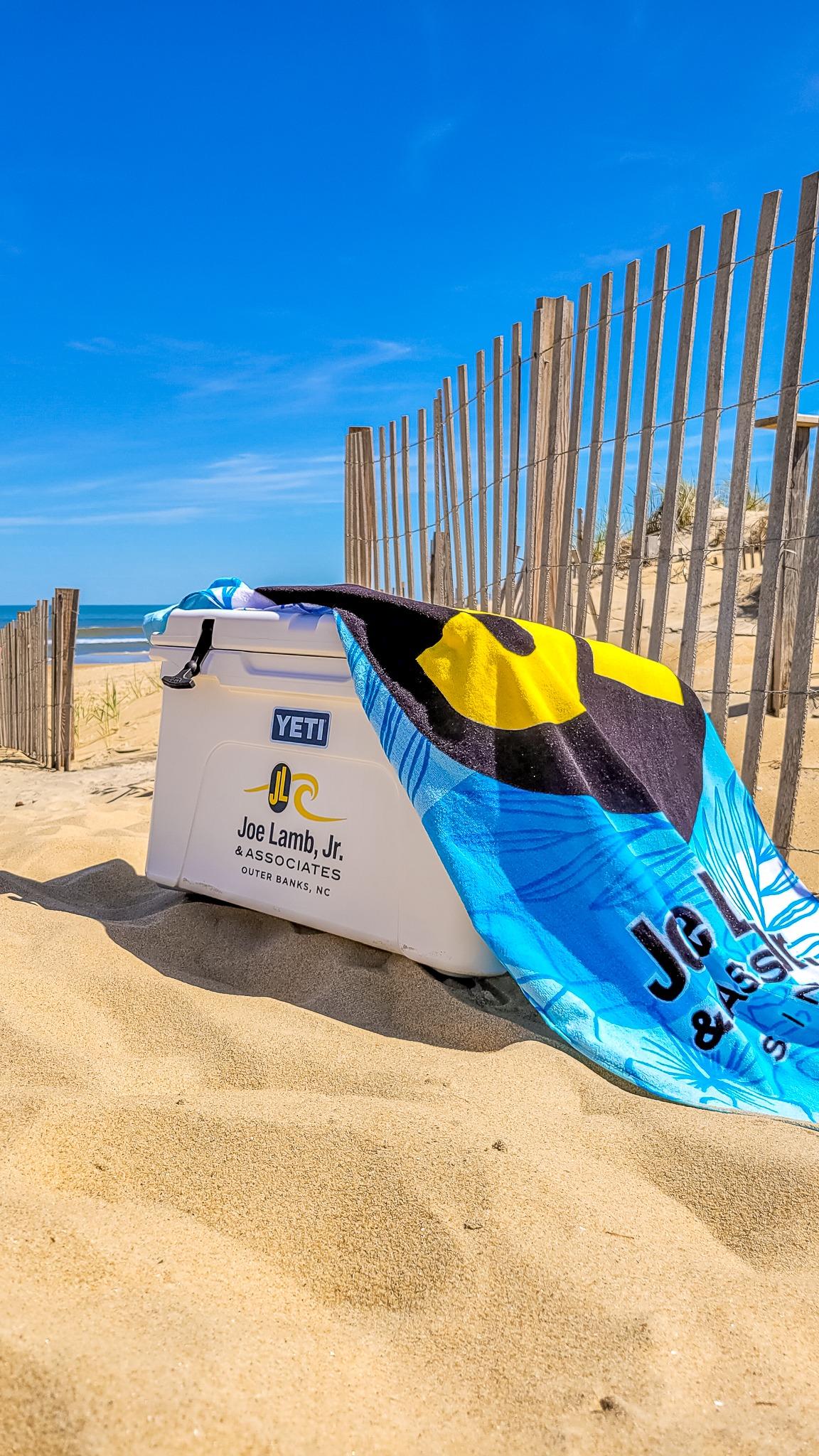 A towel over a cooler on the beach.
