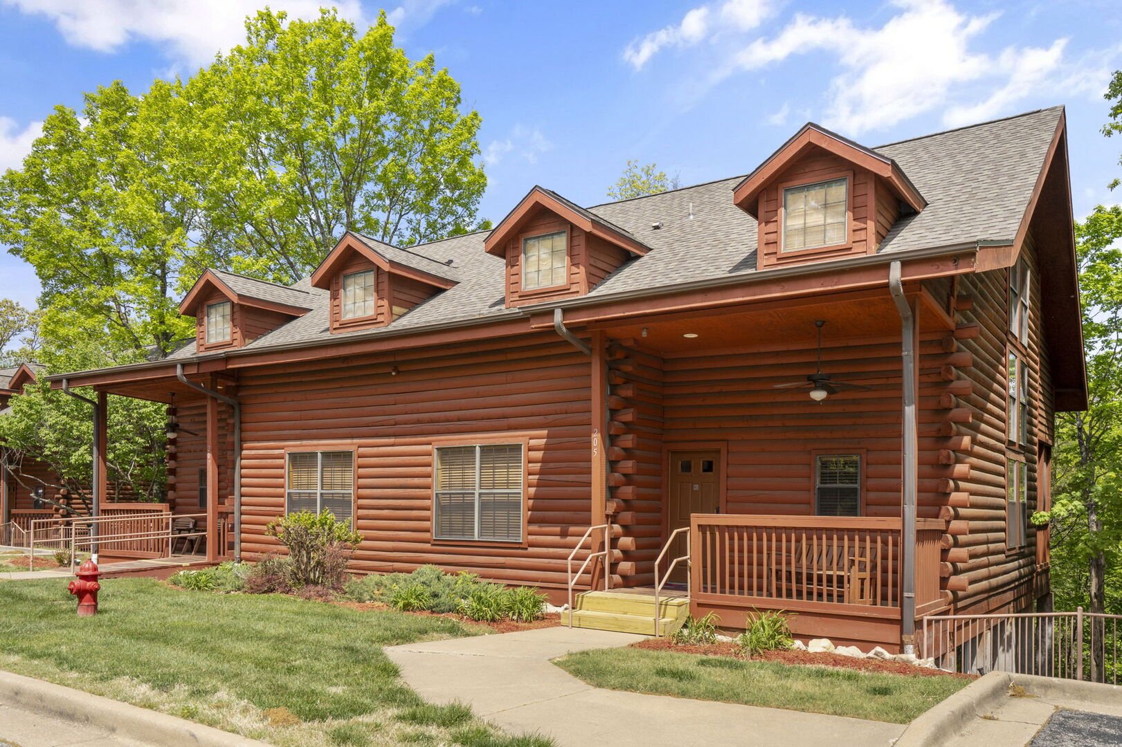 Spacious log cabin exterior surrounded by trees, featuring covered porch and multiple windows in Branson 3–4 bedroom vacation rental.