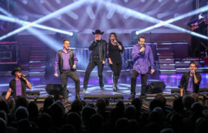 A band performing energetically on stage during a live concert, captivating the audience with their music.