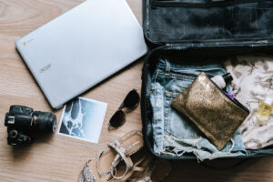A wooden table displays a laptop, a fashionable purse, and a cute pair of shoes