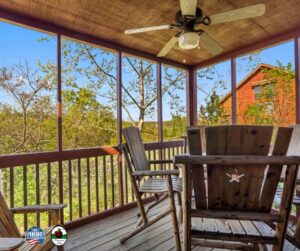 A porch featuring rocking chairs and a ceiling fan, creating a serene outdoor relaxation space.