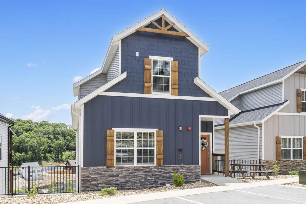 Two-storey navy blue Branson rental lodge with a stone base and a level walkway from the parking area