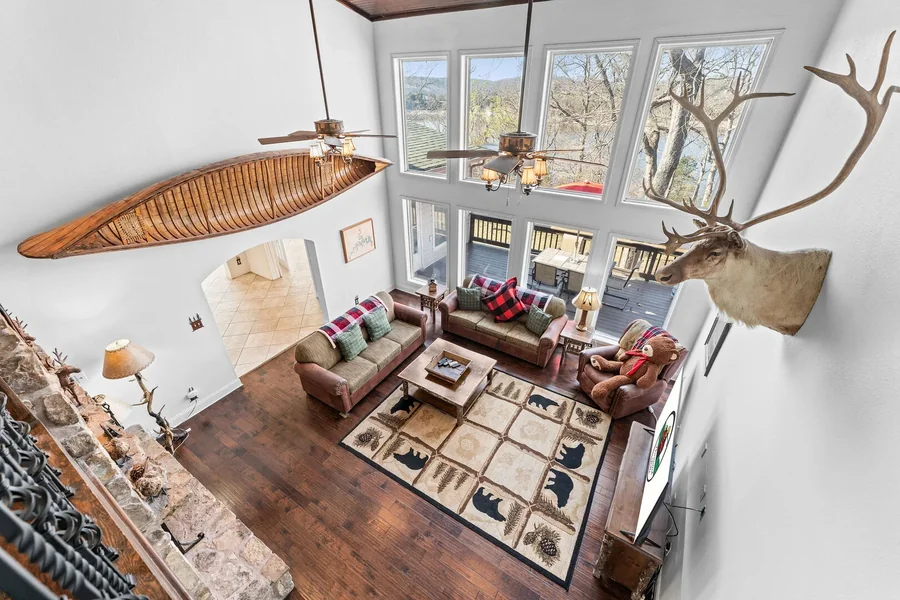 Rustic cabin living room with vaulted ceiling and lake-view windows, style of Branson cabin rental near Thunder Ridge Nature Arena