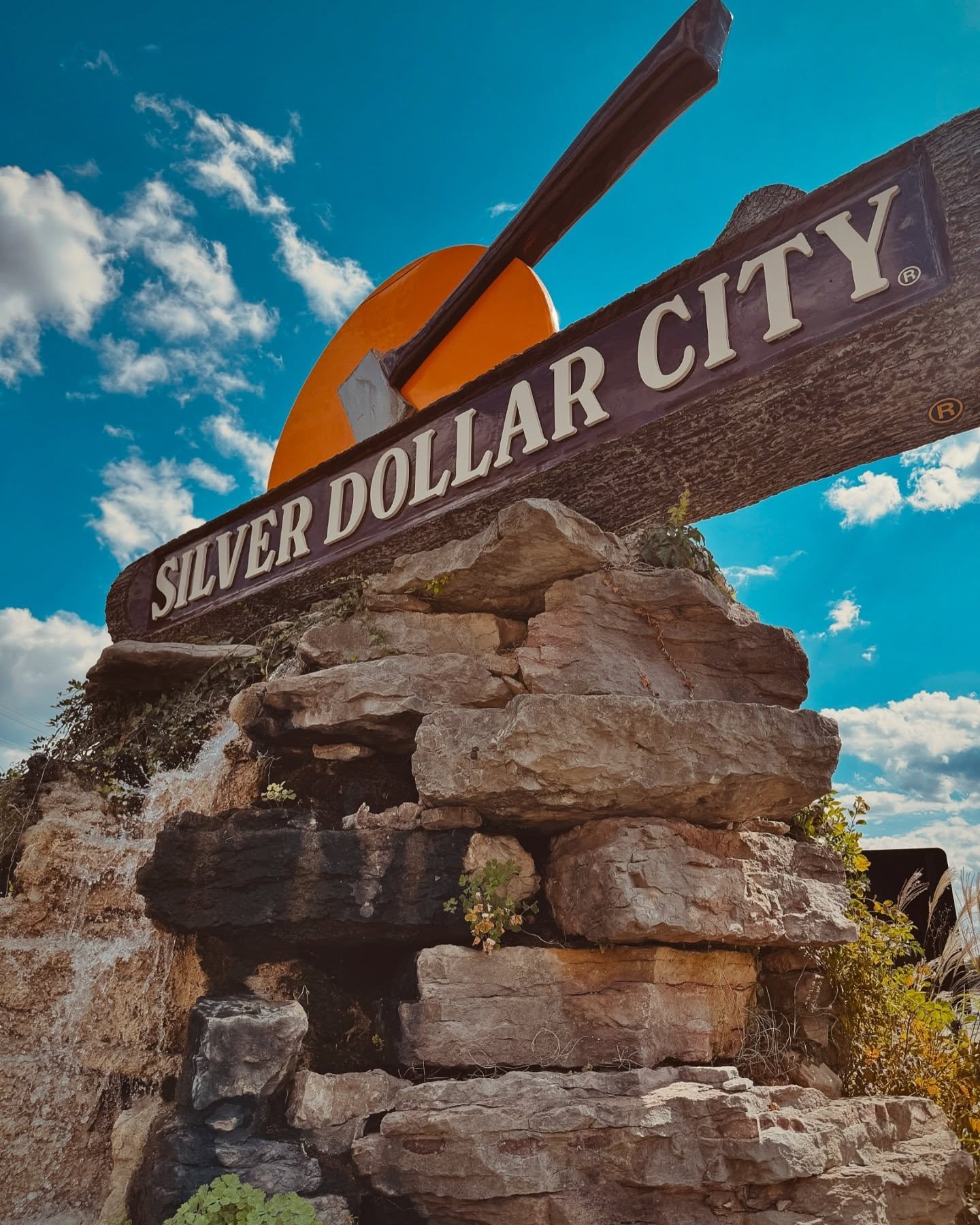 Silver Dollar City entrance sign mounted on a stacked limestone rock formation under a blue sky in Branson, Missouri