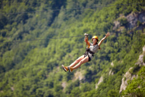 Happy young cheerful female tourist wearing casual clothes in a zipline