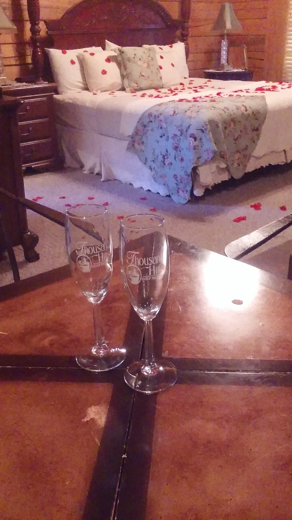 An inviting bedroom with a well-made bed, a table, and two glasses positioned atop it.