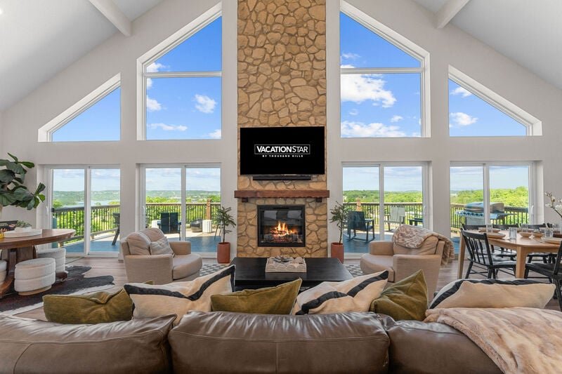 Great room with a stone fireplace and vaulted windows in a Wilderness Mountain lake home in Kimberling City, a cozy place to wait out rain