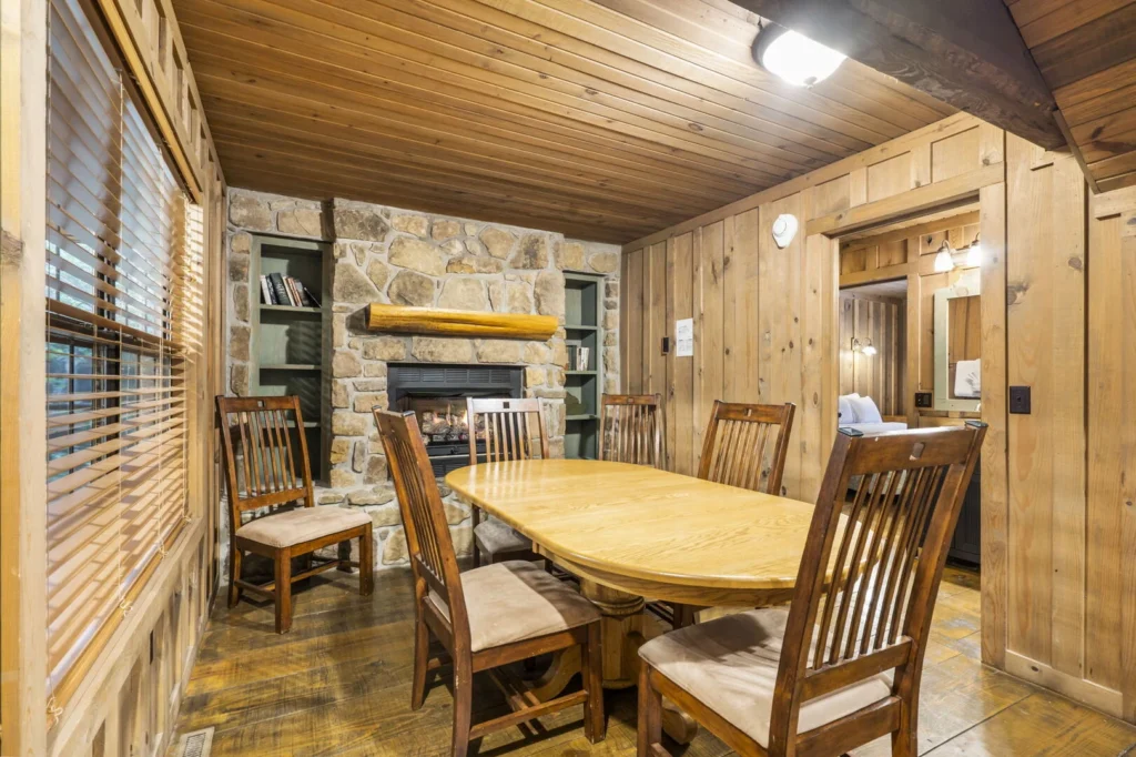 Wood-paneled dining room in a Branson vacation rental with a lit stone gas fireplace and an oval table seating six