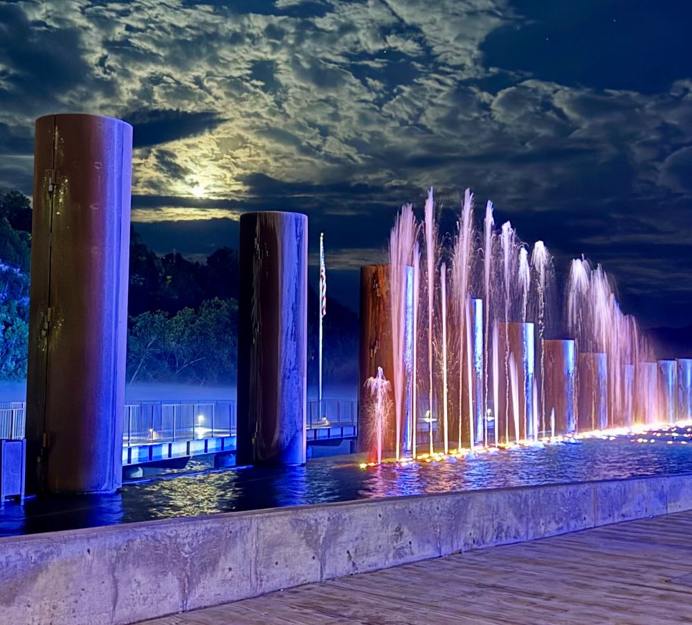 Branson Landing fountains lit blue and pink under a full moon on a foggy night in Branson, Missouri
